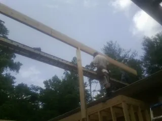 Carpenter setting a ridge beam over a new addition frame — Ice Dam Removal by Roofing Brothers in Little Neck