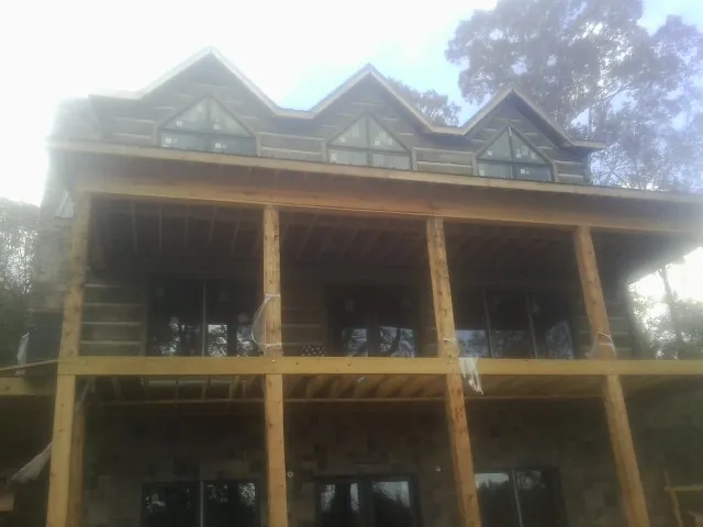 Dormers and porch framing on a large log home under construction — Roof Coating work by our crew in Little Neck