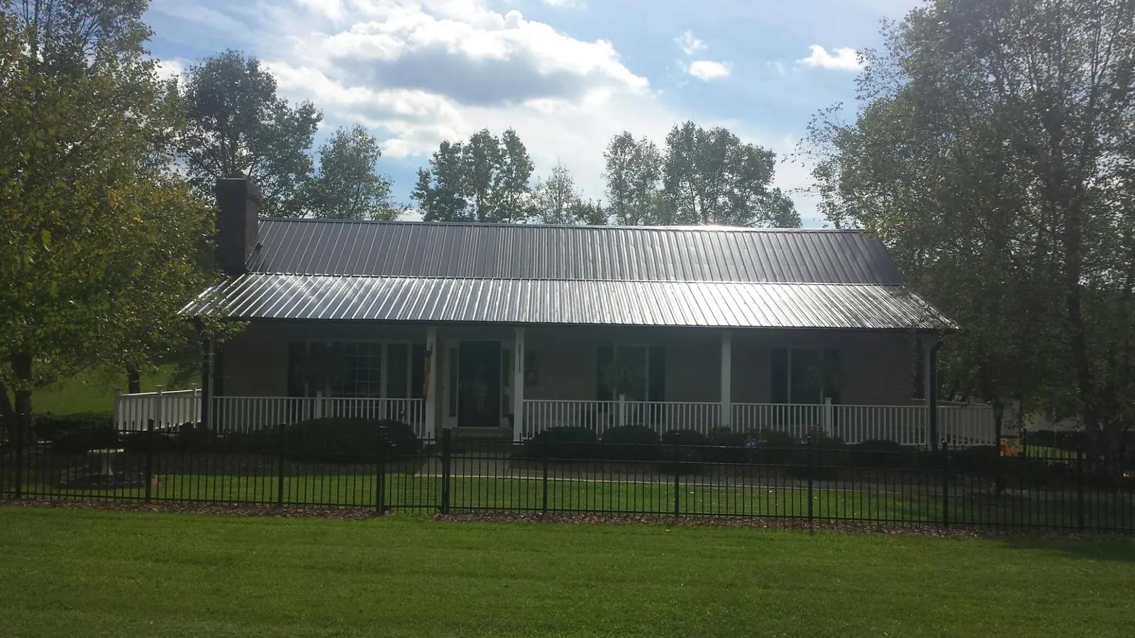 Gray metal roof on a brick ranch with a full width front porch — Gutter Guard Installation work by our crew in Little Neck