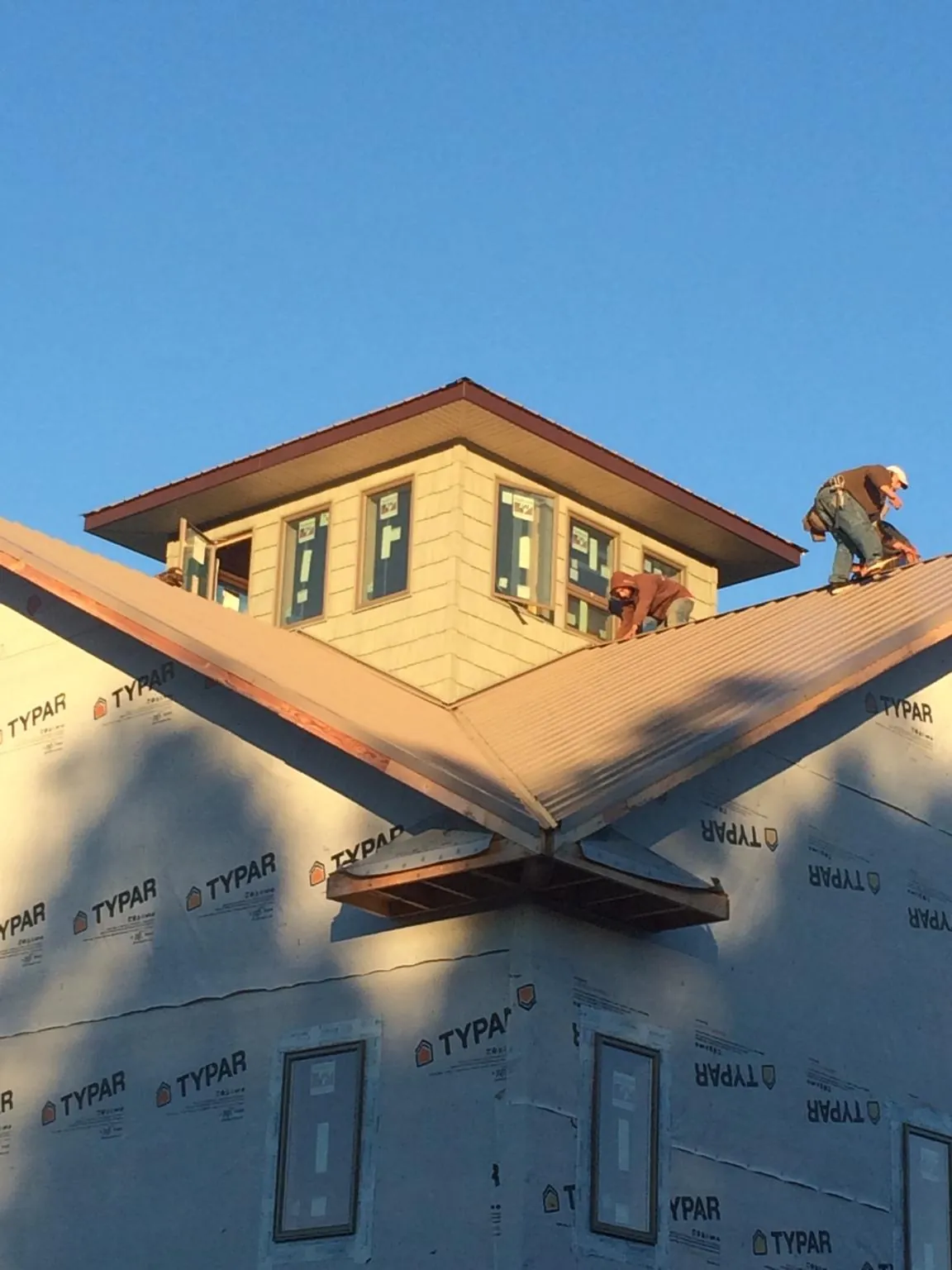 Roofers working around a rooftop cupola on a new metal roof at sunset — Roof Waterproofing in Little Neck by Roofing Brothers